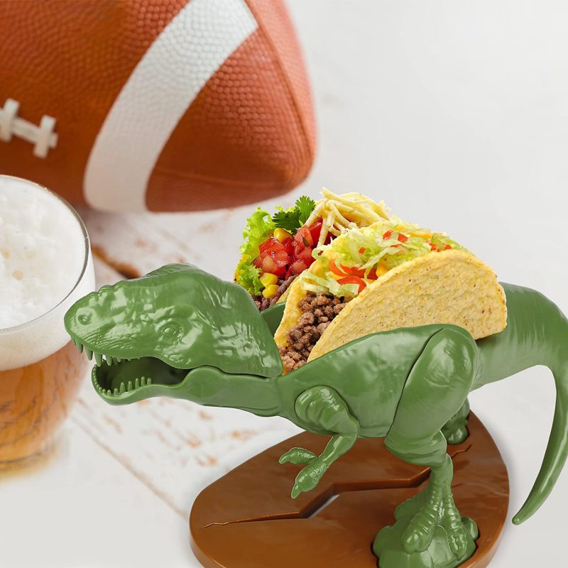 If you're pterotorial about your tacos our Tacosaurus Rex Taco Holder is just the lizard king for the job! Now the hunted becomes the hunter! Keep this fiercely loyal tyrannosaurus rex fed with yummy noms, and he'll be raptor round your finger! And while he's best know for defending your tacos, he also enjoys a good BLT - bacon, lettuce, tyrannosaurus rex! THE ULTIMATE TACO HOLDER: Tacosaurus Rex Taco Holder. Holds 2 Tacos! NOT JUST FOR TACOS: Try it with Waffles, Toast, Sandwiches, Ice Cream Tacos, Crackers and more! FUN FOR ALL AGES: Perfect for kids and adults that are looking to add a bit of fun to the dinner table! FOOD-SAFE: BPA free, lead free and phthalate free. EASY TO CLEAN: Top rack dishwasher safe. Not microwaveable. Watch with delight as our Tacosaurus Rex turns your little monsters into content and docile critters. This prehistoric titan carries two tacos and makes every meal a thrilling adventure! This 100-percent food-safe polypropylene taco holder can handle just about anything young children do to them. It's the ultimate gift for dinosaur lovers! BPA free, lead free and phthalate free to meet or exceed current safety standards. Dimensions: 9.5 inches tall x 4.5 inches wide x 6 inches long. Our Tacosaurus Rex Taco Holder is dinomite!